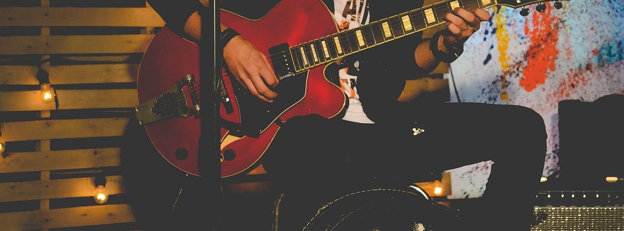 Man A man sitting on a speaker playing a guitar